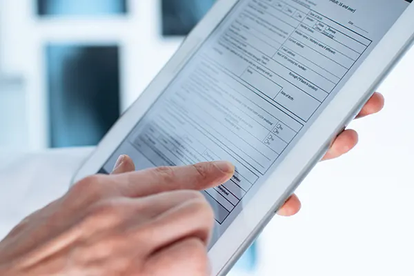 A dentist helping her patient fill out insurance paperwork on a clipboard